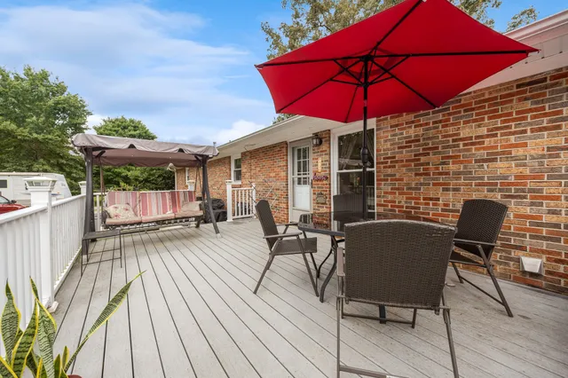a view of a patio with table and chairs under an umbrella with wooden floor
