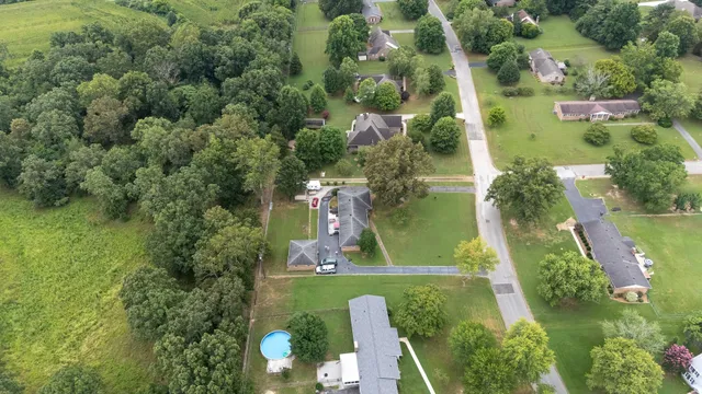 an aerial view of a residential houses with outdoor space and trees all around