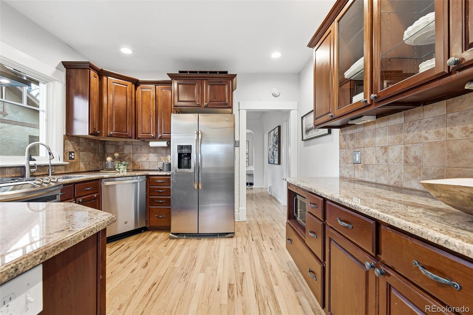 1318 South York Street Denver, CO 80210 - Photo 12 of 49 a kitchen with stainless steel appliances granite countertop a refrigerator a sink dishwasher a stove with wooden cabinets and floor