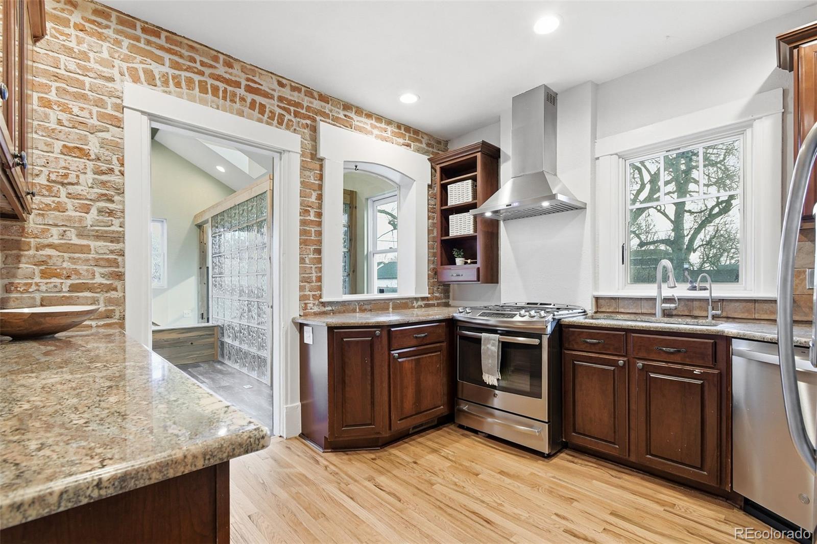 1318 South York Street Denver, CO 80210 - Photo 13 of 49 a kitchen with stainless steel appliances granite countertop hardwood floor sink stove and wooden cabinets