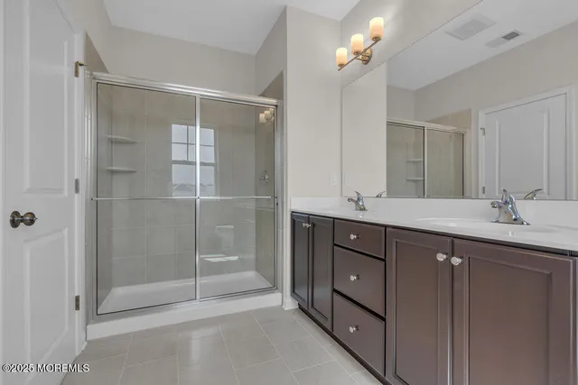 a bathroom with double vanity and a mirror