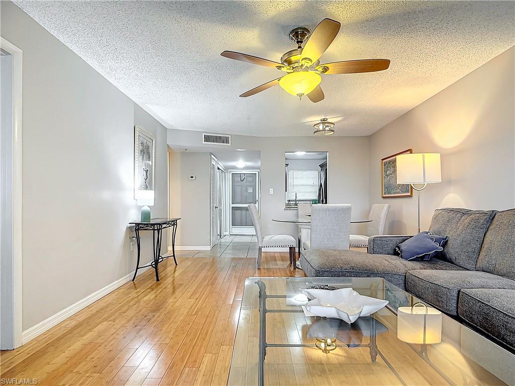 175 Turtle Lake Court, Unit 310 Naples, FL 34105 - Photo 12 of 34 Living room with hardwood / wood-style flooring, ceiling fan, and a textured ceiling