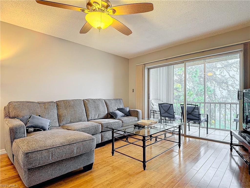 175 Turtle Lake Court, Unit 310 Naples, FL 34105 - Photo 13 of 34 Living room featuring hardwood / wood-style floors, a textured ceiling, and ceiling fan
