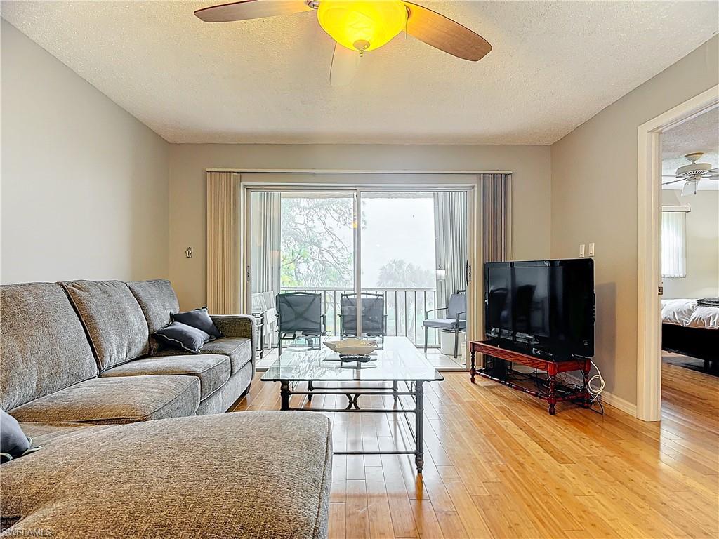 175 Turtle Lake Court, Unit 310 Naples, FL 34105 - Photo 15 of 34 Living room with ceiling fan, wood-type flooring, and a textured ceiling