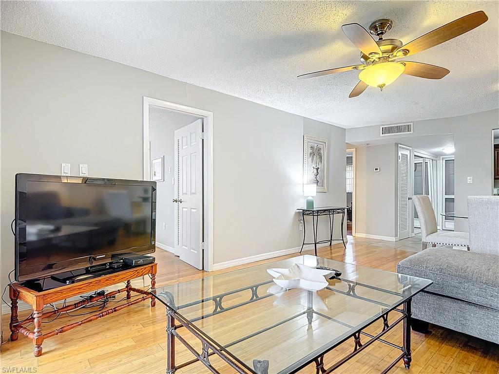 175 Turtle Lake Court, Unit 310 Naples, FL 34105 - Photo 16 of 34 Living room with ceiling fan, a textured ceiling, and light wood-type flooring