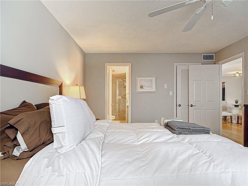 175 Turtle Lake Court, Unit 310 Naples, FL 34105 - Photo 18 of 34 Bedroom featuring ceiling fan, ensuite bathroom, and a textured ceiling