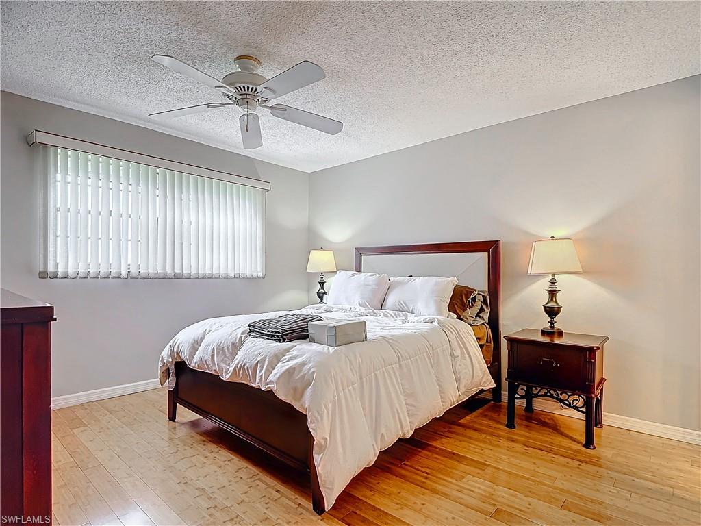 175 Turtle Lake Court, Unit 310 Naples, FL 34105 - Photo 19 of 34 Bedroom featuring ceiling fan, hardwood / wood-style floors, and a textured ceiling