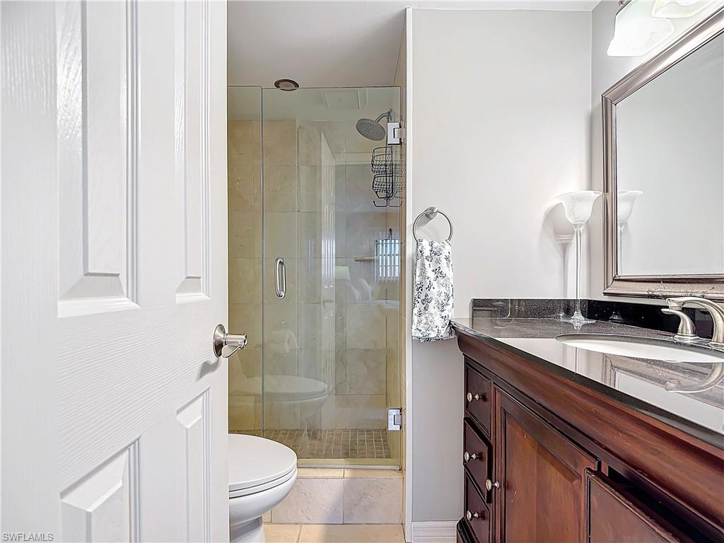 175 Turtle Lake Court, Unit 310 Naples, FL 34105 - Photo 21 of 34 Bathroom featuring vanity, an enclosed shower, and toilet