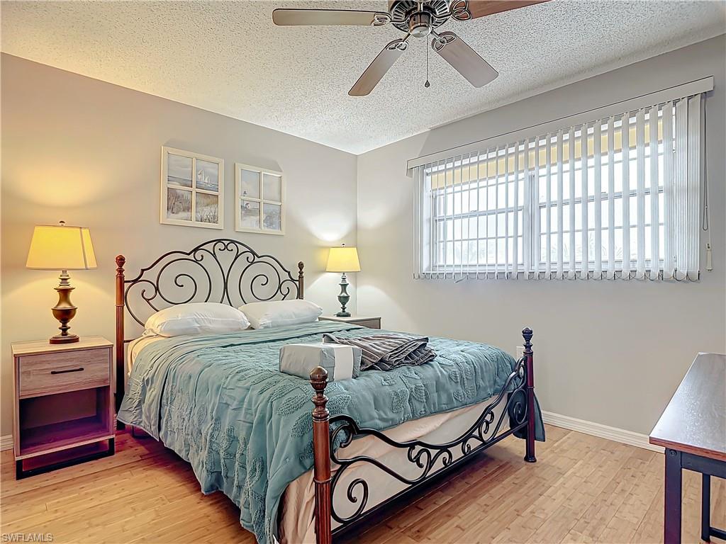 175 Turtle Lake Court, Unit 310 Naples, FL 34105 - Photo 24 of 34 Bedroom featuring wood-type flooring, ceiling fan, and a textured ceiling