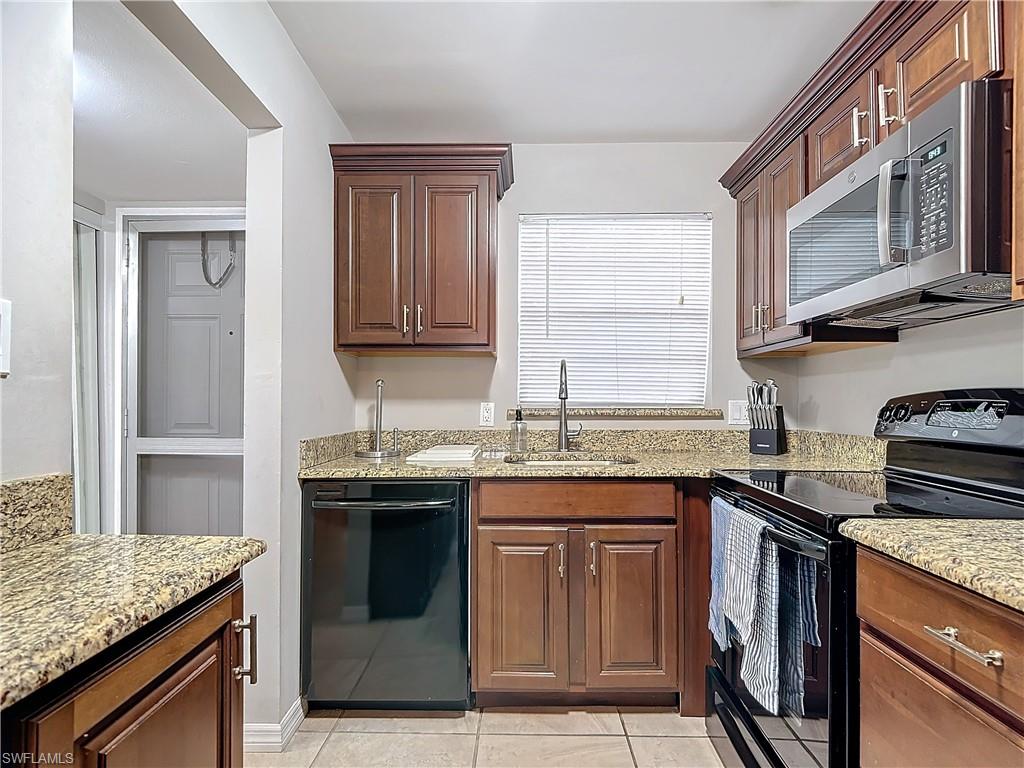 175 Turtle Lake Court, Unit 310 Naples, FL 34105 - Photo 4 of 34 Kitchen featuring sink, light tile patterned flooring, black appliances, and light stone countertops
