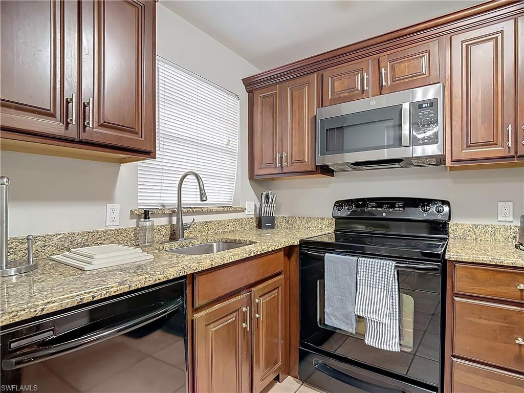 175 Turtle Lake Court, Unit 310 Naples, FL 34105 - Photo 6 of 34 Kitchen with light stone counters, sink, and black appliances