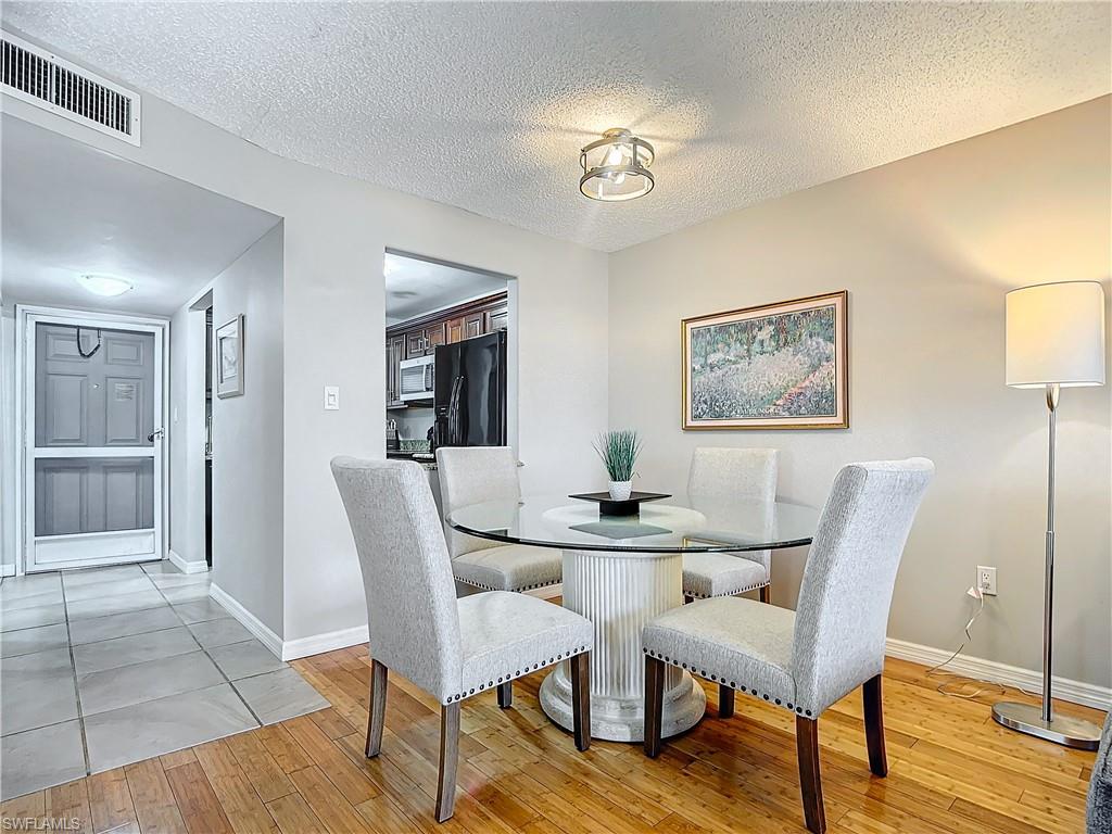 175 Turtle Lake Court, Unit 310 Naples, FL 34105 - Photo 9 of 34 Dining room featuring a textured ceiling and light hardwood / wood-style floors