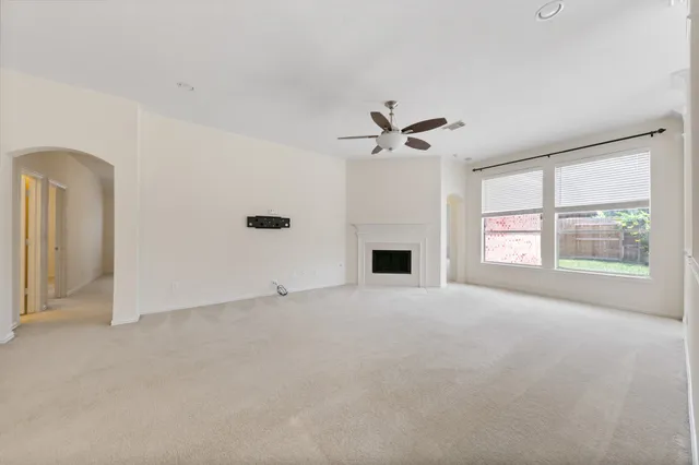 an empty room with windows and ceiling fan