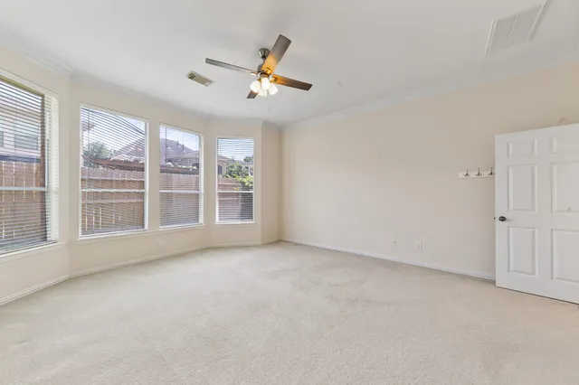 an empty room with windows and ceiling fan
