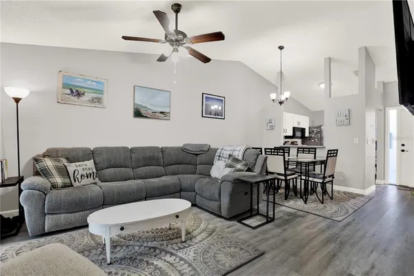 a living room with furniture kitchen view and a chandelier