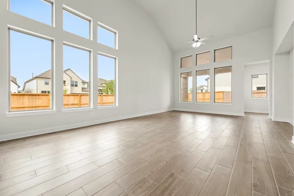 an empty room with wooden floor chandelier and windows