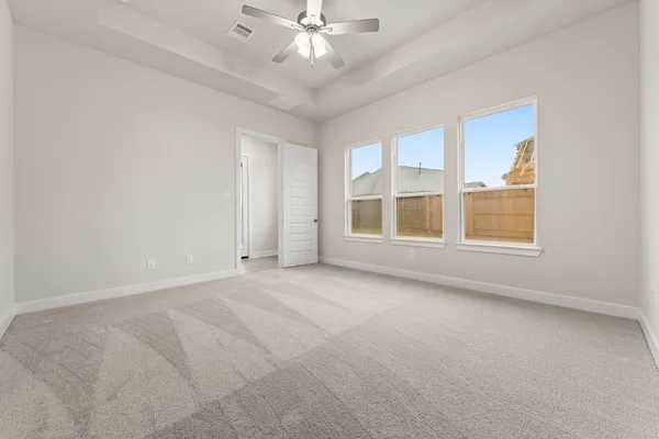 an empty room with chandelier fan and windows