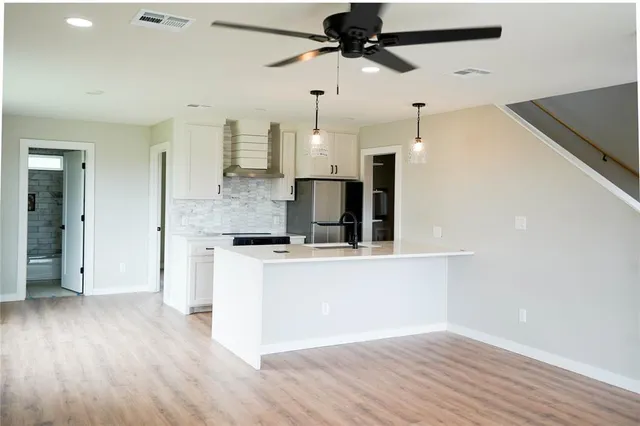a large kitchen with cabinets wooden floor and stainless steel appliances