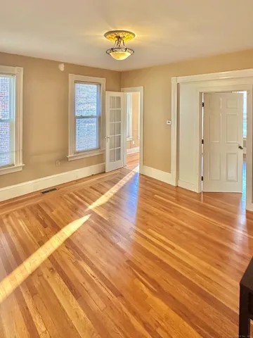 a view of an empty room with wooden floor and a window