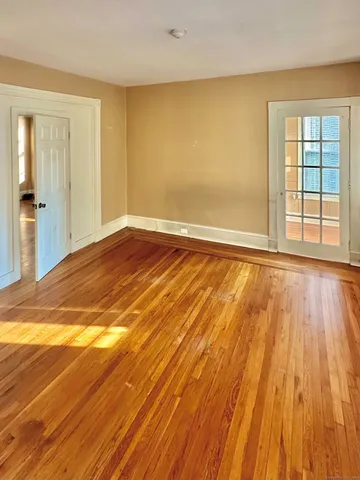 a view of an empty room with wooden floor and a window