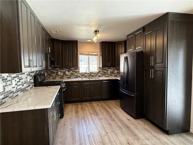 a kitchen with stainless steel appliances granite countertop a sink counter space and wooden floor
