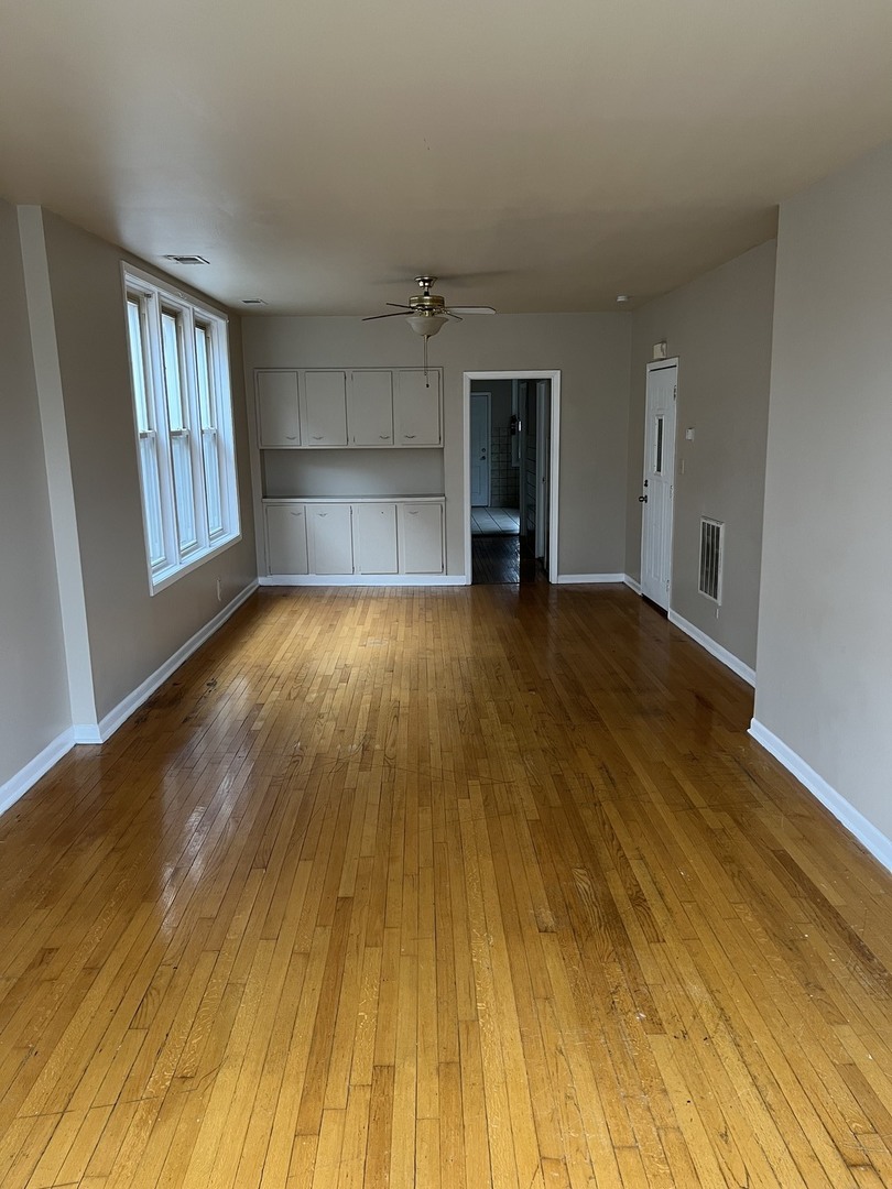Undisclosed Address Chicago, IL 60624 - Photo 3 of 16 a view of an empty room with wooden floor and a window
