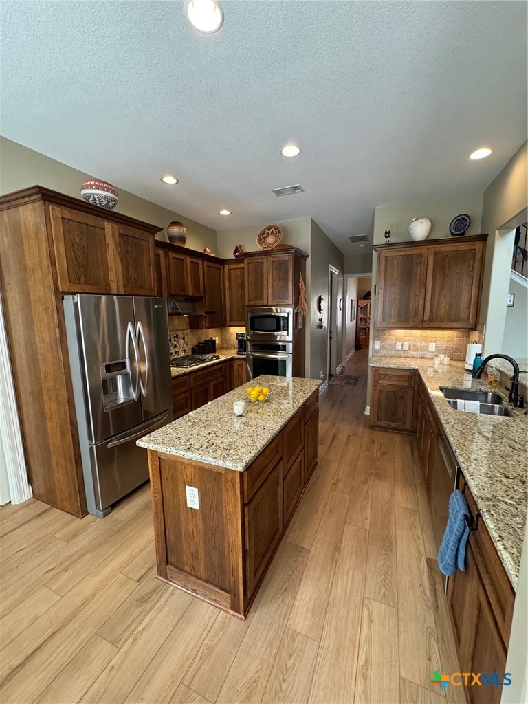 2306 Arroyo Grande Leander, TX 78641 - Photo 3 of 44 a kitchen with stainless steel appliances granite countertop a stove top oven a refrigerator a sink and dishwasher a oven with wooden floor