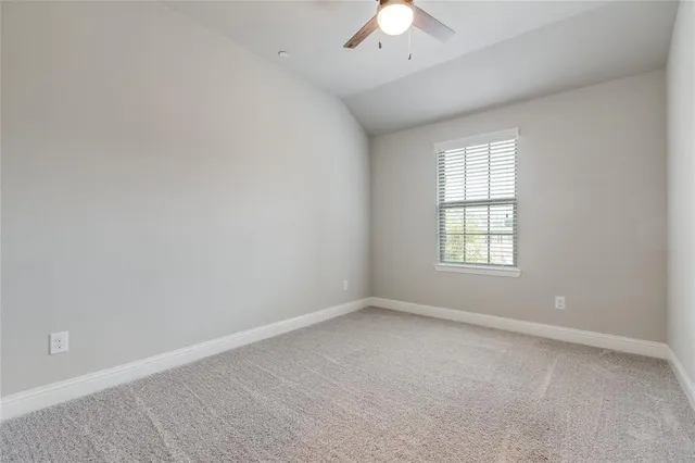 an empty room with a chandelier fan and windows