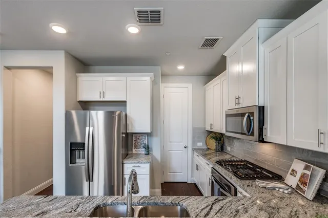a kitchen with stainless steel appliances granite countertop a refrigerator and a stove top oven