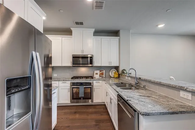 a kitchen with stainless steel appliances granite countertop a sink stove and refrigerator