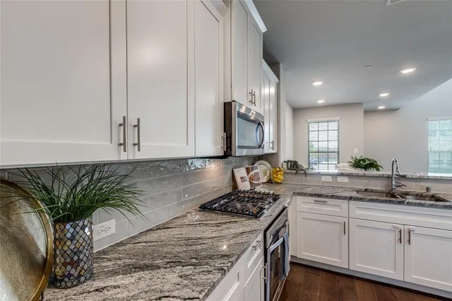 a kitchen with a granite countertop sink a stove and cabinets