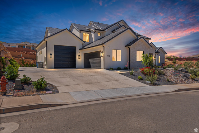 1192 East Corral Way Washington, UT 84780 - Photo 6 of 81 Modern stucco and stone exterior featuring a multi-gabled roofline and dark garage doors