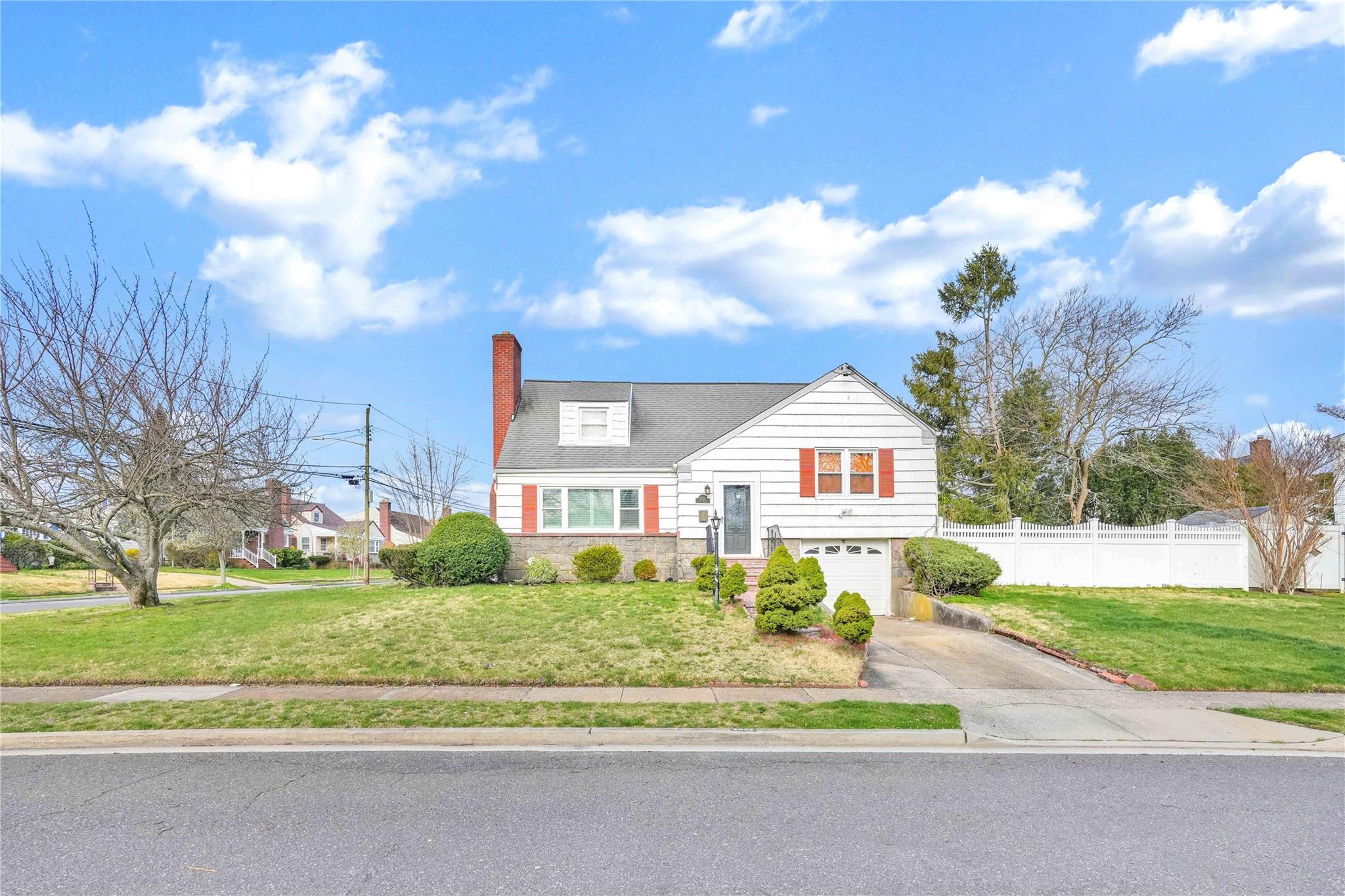 2632 Fox Road Baldwin, NY 11510 - Photo 1 of 1 View of front of home with fence, an attached garage, aphalt driveway, a front lawn, and a chimney