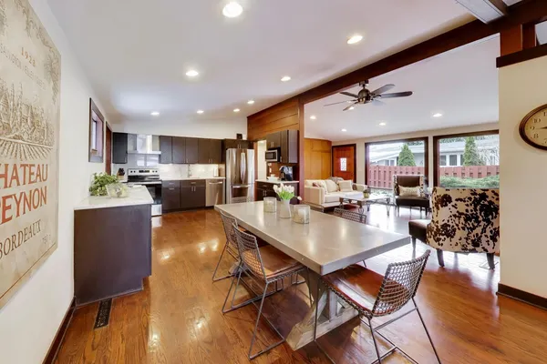 a dining room with stainless steel appliances furniture large window and wooden floor