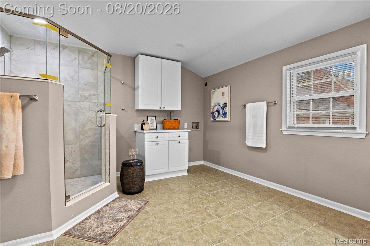429 Moran Road Grosse Pointe, MI 48236 - Photo 14 of 36 Spa-inspired primary bathroom featuring a frameless glass-enclosed shower with tile surround, dual-sink vanity with white cabinetry and ample storage, heated towel rack, and tile flooring throughout