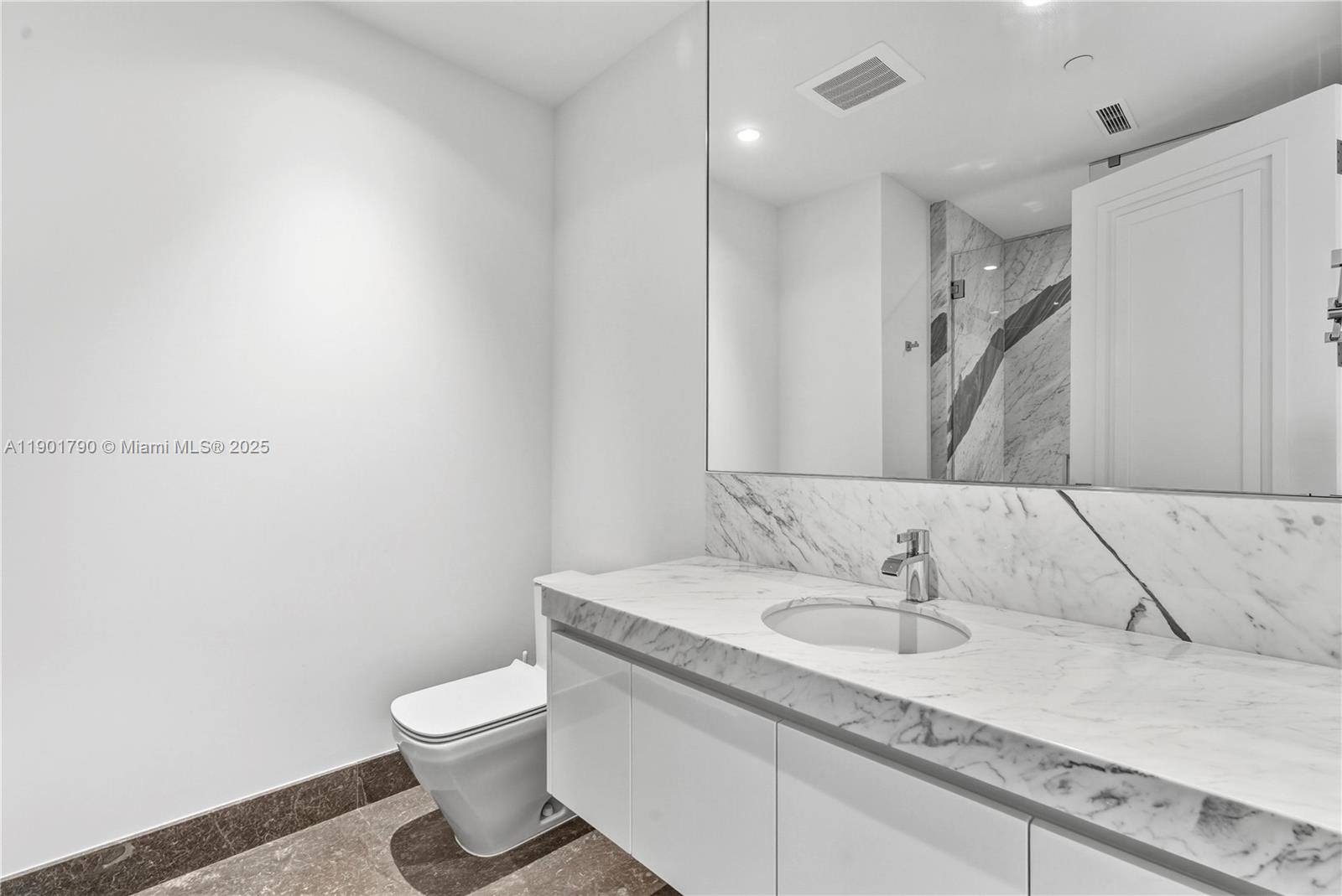 17901 Collins Avenue, Unit 1803 Sunny Isles Beach, FL 33160 - Photo 20 of 57 a bathroom with a granite countertop sink a toilet and a mirror