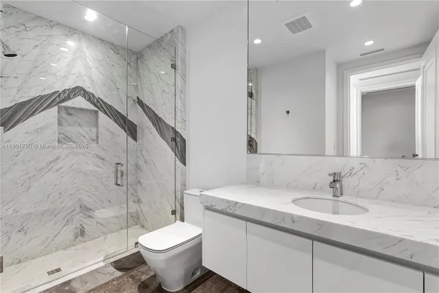 a bathroom with a granite countertop sink a toilet a mirror and shower