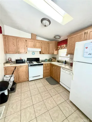 a kitchen with granite countertop a sink a stove top oven and cabinetry