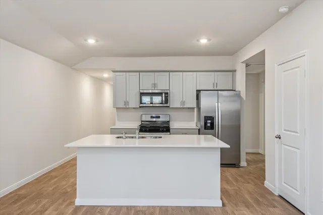 a kitchen with kitchen island a counter top space cabinets stainless steel appliances and cabinets