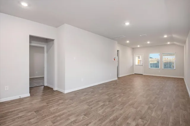 a view of an empty room with window and wooden floor