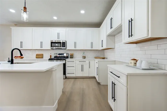 a kitchen with white cabinets a sink stove and refrigerator