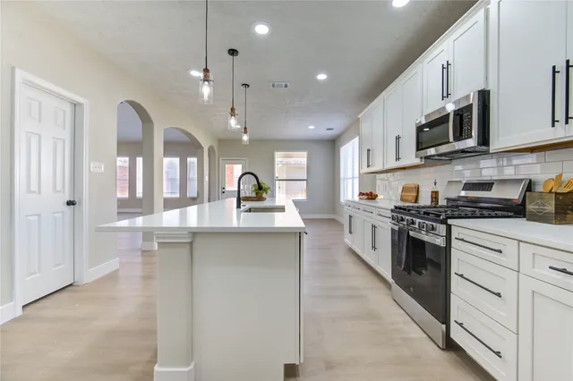 a large kitchen with stainless steel appliances lots of counter space and a sink