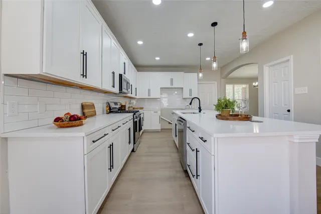 a kitchen with kitchen island granite countertop lots of white cabinets and white appliances