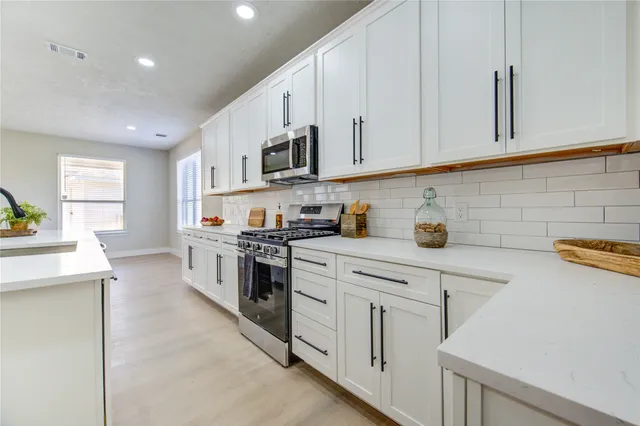 a kitchen with stainless steel appliances granite countertop white cabinets a sink and dishwasher