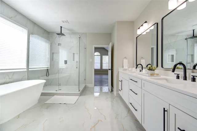a spacious bathroom with double vanity a mirror a shower and a bathtub