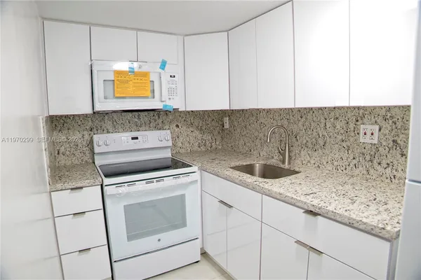 a kitchen with granite countertop white cabinets and white appliances