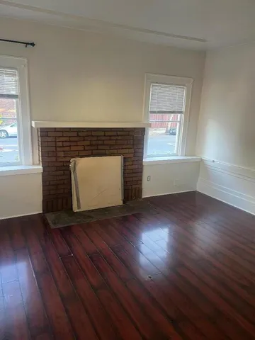 an empty room with wooden floor and fireplace