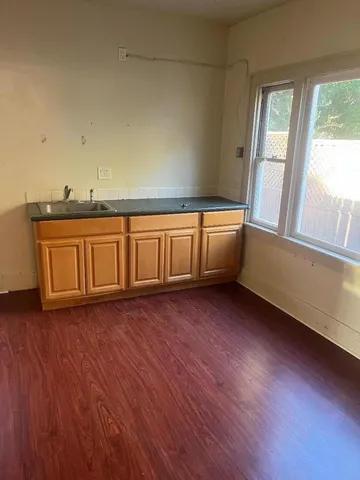 a view of an empty room with a window and wooden floor