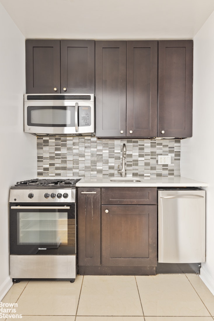 435 East 85th Street, Unit 4C Manhattan, NY 10028 - Photo 5 of 9 a kitchen with stainless steel appliances granite countertop a stove a sink and a microwave