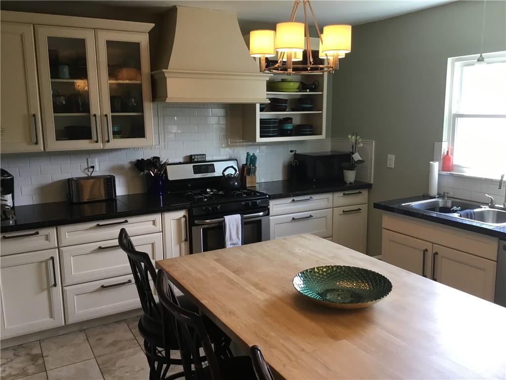 104 Sumner Avenue Vandergrift, PA 15690 - Photo 11 of 26 a kitchen with a stove a sink a dining table and chairs